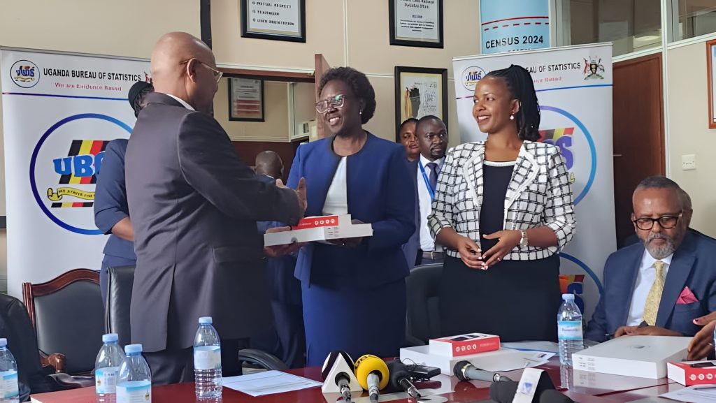 Dr. Mukiza,  the Executive Director of Uganda Bureau of Statists (UBOS) handing over 200 Tablets to Prof. Ezati ( center).